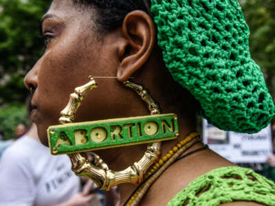 A woman at an abortion rally wears earrings that say "abortion"