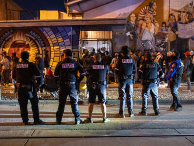 Police watch as immigrants enter a migrant shelter on January 6, 2023, in El Paso, Texas.