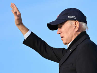 Joe Biden waves to supporters out of frame while wearing a baseball cap