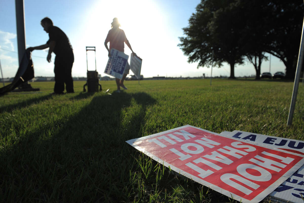 People opposed to the death penalty pick up signs as they gather to demonstrate against the execution of John Ruthell Henry near the Florida State Prison on June 18, 2014, in Raiford, Florida.