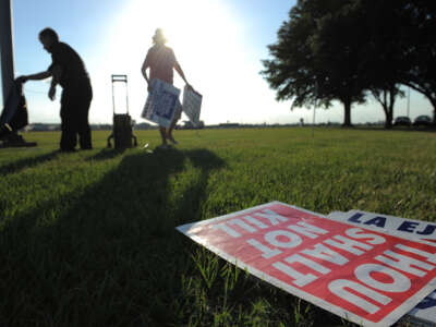 People opposed to the death penalty pick up signs as they gather to demonstrate against the execution of John Ruthell Henry near the Florida State Prison on June 18, 2014, in Raiford, Florida.
