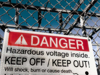 A sign warns people about the dangers of shock from high voltage outside an electric power plant.