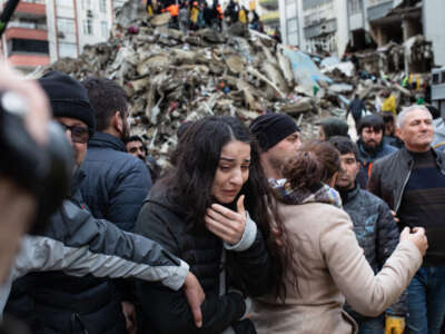 A woman reacts as rescuers search for survivors through the rubble of collapsed buildings in Adana, Turkey, on February 6, 2023, after a 7,8 magnitude earthquake struck the country's south-east.