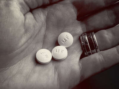 Three RU-486 Mifeprex abortion pills are held in a hand.