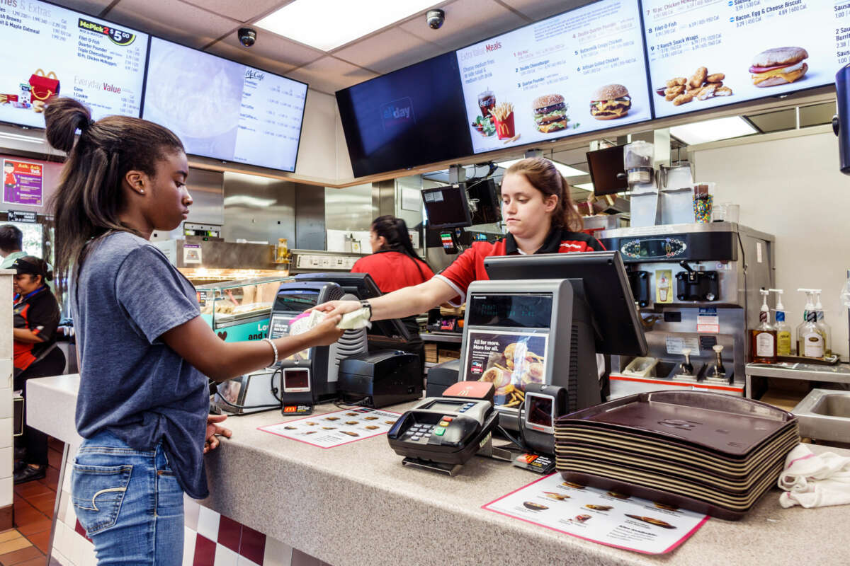 A teen working at McDonald's hands another teen change