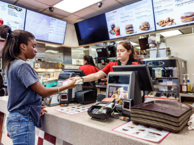 A teen working at McDonald's hands another teen change