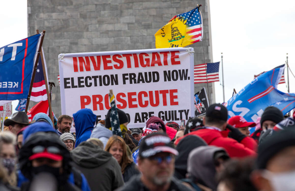 Crowds gather outside the U.S. Capitol, in front of the Washington Monument, for the Stop the Steal rally on January 6, 2021, in Washington, D.C. There is a banner reading: Investigated Election Fraud Now. Prosecute Those Who Are Guilty.