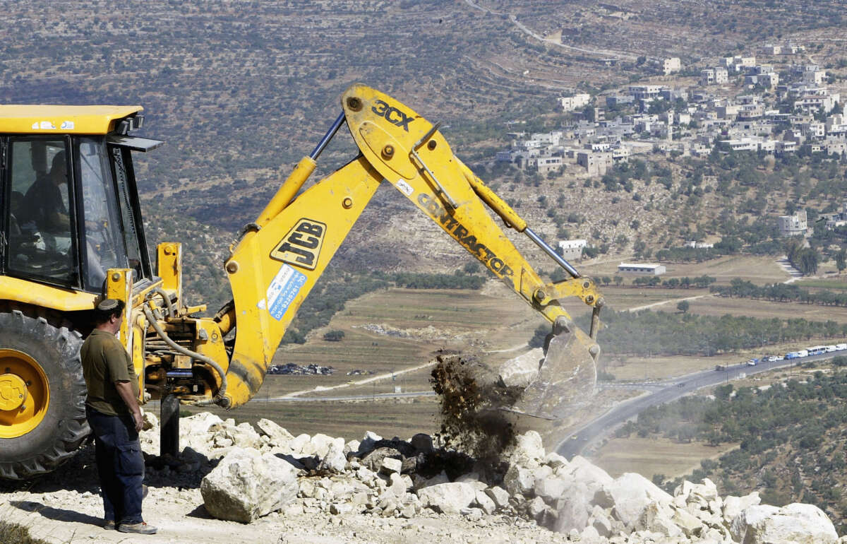 Israeli contractors secure the dirt road which encircles the illegal outpost of Givat Haro'eh, on June 22, 2004, in Givat Haro'eh, West Bank.