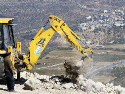 Israeli contractors secure the dirt road which encircles the illegal outpost of Givat Haro'eh, on June 22, 2004, in Givat Haro'eh, West Bank.