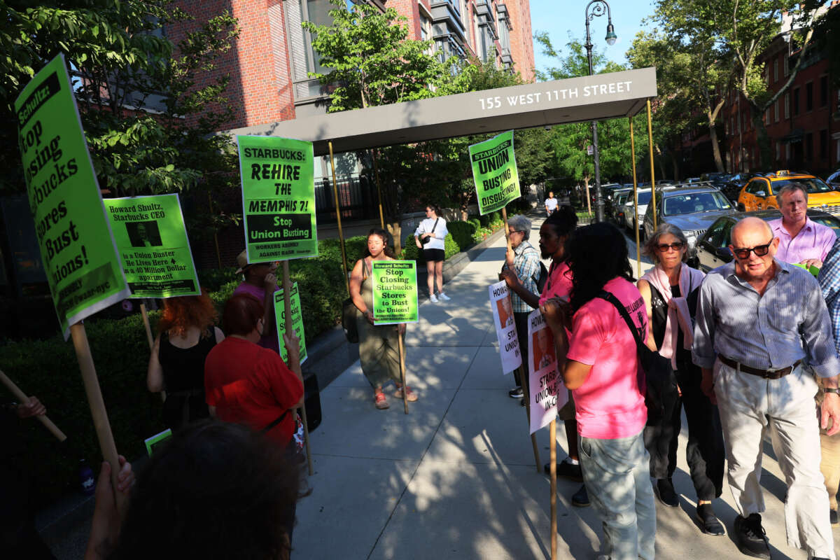 People walk past activists as they participate in an event dubbed the Un-Birthday Party and picket line for Starbucks CEO Howard Schultz on July 19, 2022, in New York City.