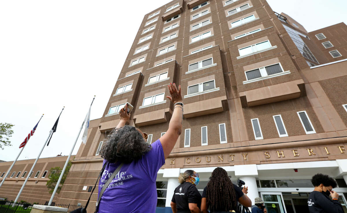 Andrea James, executive director of the National Council For Incarcerated and Formerly Incarcerated Women and Girls, waves to people banging on the windows of the South Bay House of Correction in Boston on May 9, 2021. Calling for the release of incarcerated women, members of several groups rallied at MCI Framingham and then rode in a caravan to Boston, during the continuing coronavirus pandemic.