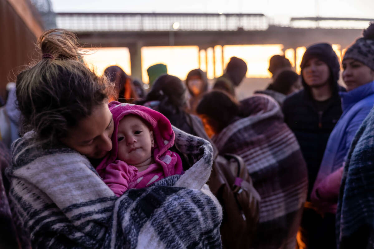 A Venezuelan immigrant holds her daughter after spending the night camped alongside the U.S.-Mexico border fence on December 22, 2022, in El Paso, Texas.