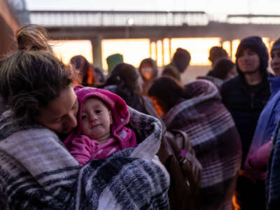 A Venezuelan immigrant holds her daughter after spending the night camped alongside the U.S.-Mexico border fence on December 22, 2022, in El Paso, Texas.