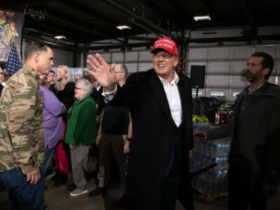 Donald Trump Jr., right, looks on as former President Donald Trump, center, waves while departing after an event at the East Palestine Fire Department in East Palestine, Ohio, on February 22, 2023.