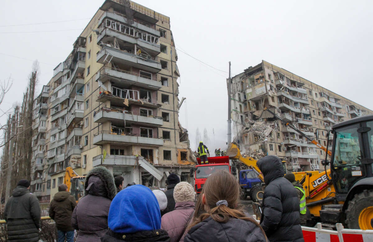 Onlookers watch a search and rescue operation at an apartment block hit by a Russian-launched rocket during a massive missile attack on Dnipro in central Ukraine on January 14, 2023.