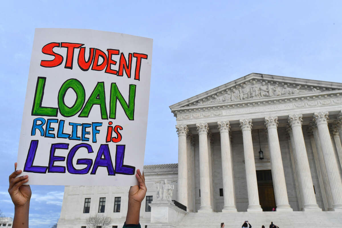 A protester holds up a sign reading "STUDENT LOAN RELIEF IS LEGAL" outside of the United States Supreme Court building