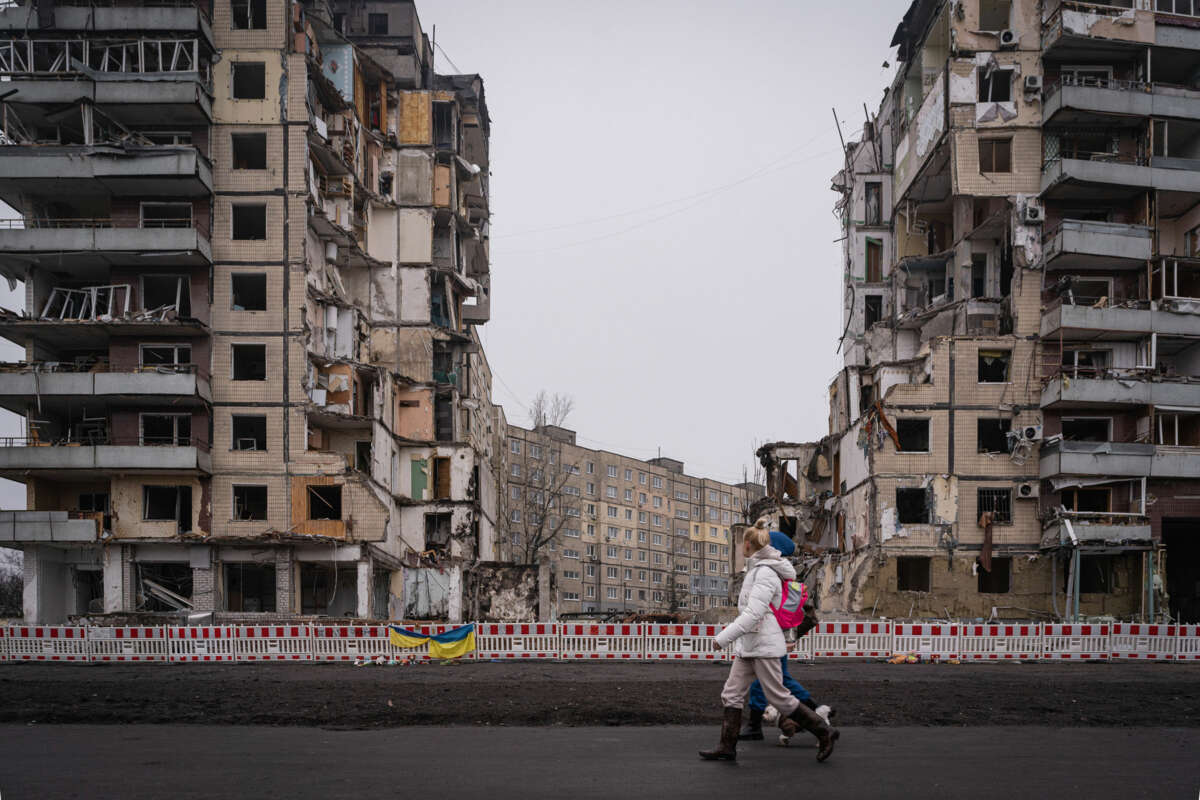 People walk by the rubble of partially-destroyed apartment buildings