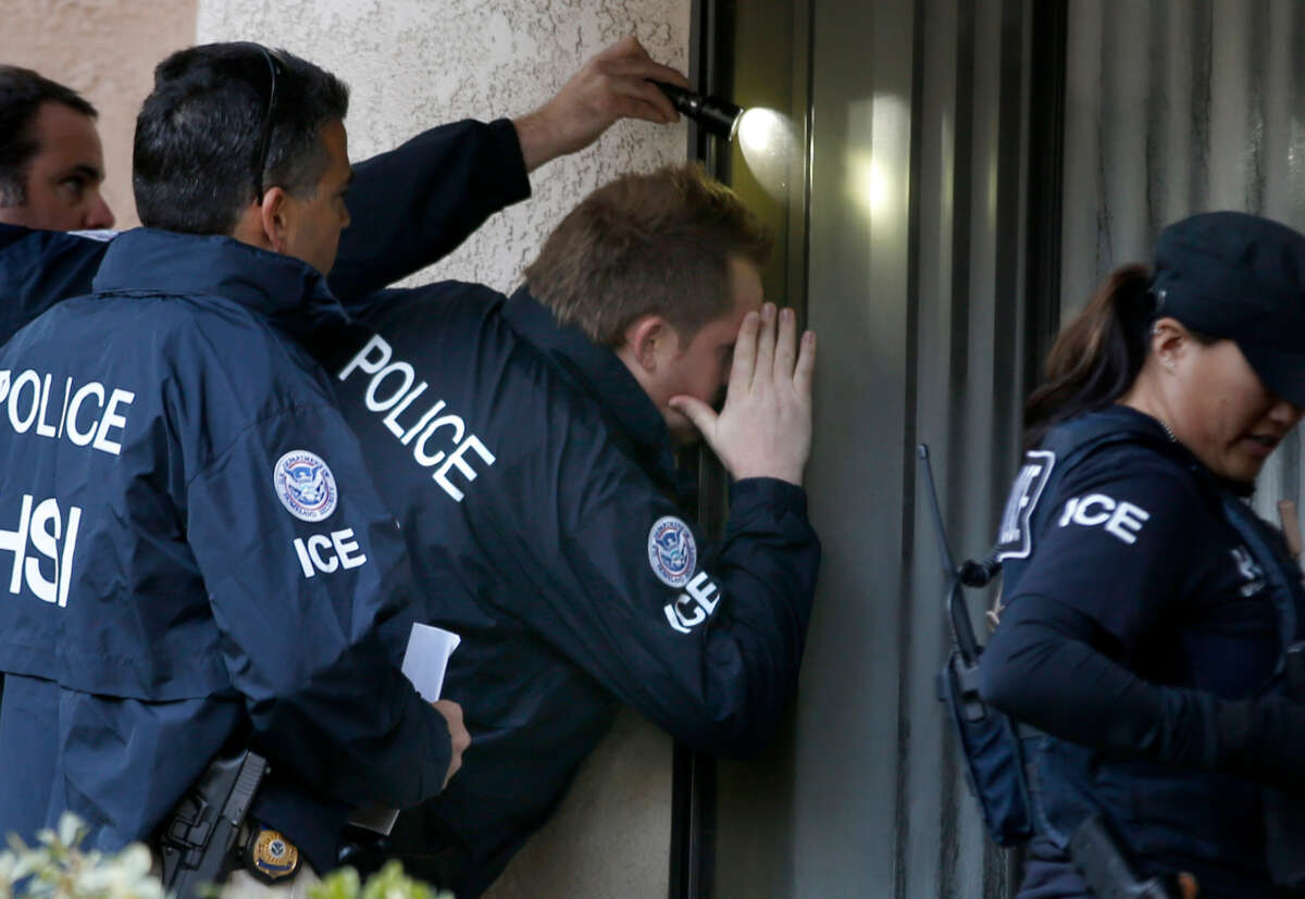 Immigration and Customs Enforcement agents from the Department of Homeland Security look into the window of an apartment while executing search warrants on March 3, 2015, in Rowland Heights, California.