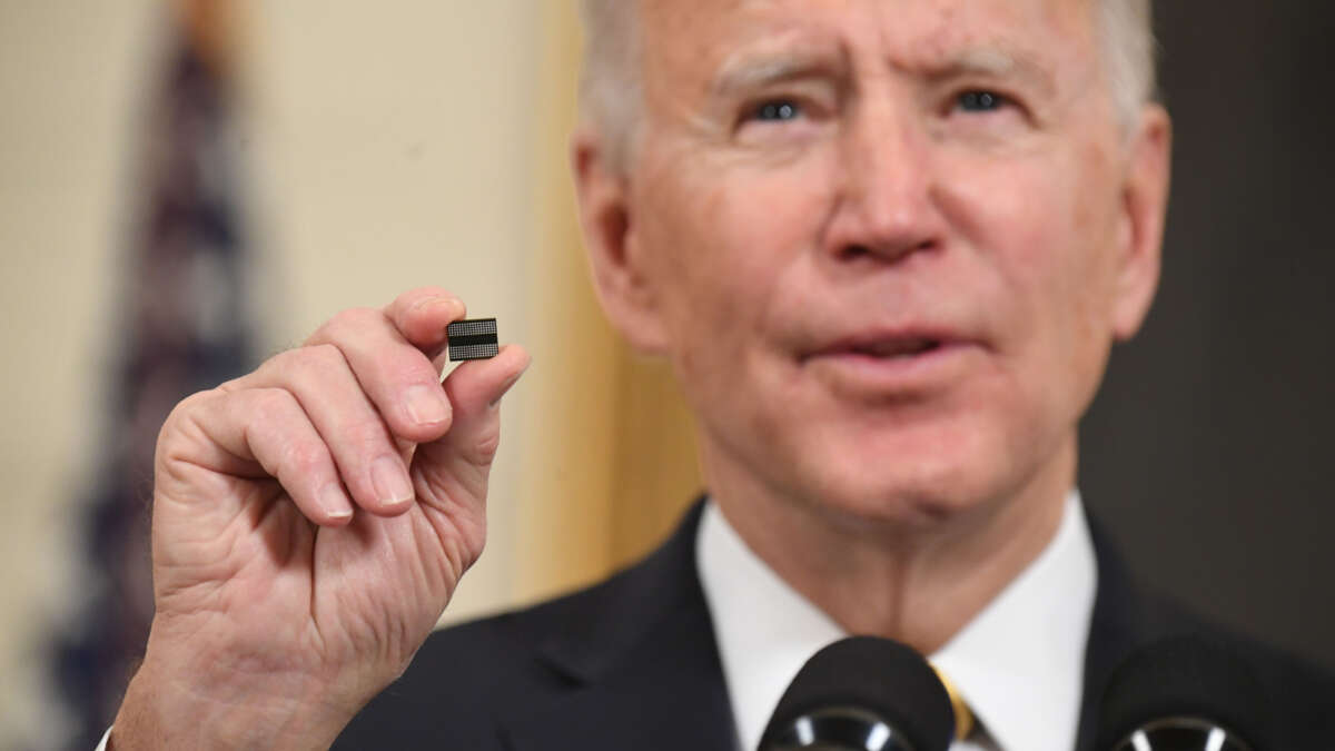 President Joe Biden holds a microchip as he speaks before signing an executive order on securing critical supply chains, in the State Dining Room of the White House in Washington, D.C., on February 24, 2021.