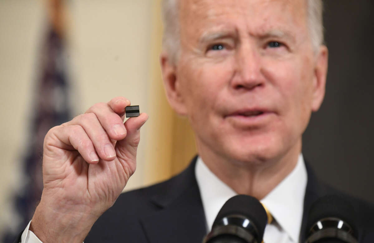 President Joe Biden holds a microchip as he speaks before signing an executive order on securing critical supply chains, in the State Dining Room of the White House in Washington, D.C., on February 24, 2021.
