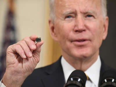 President Joe Biden holds a microchip as he speaks before signing an executive order on securing critical supply chains, in the State Dining Room of the White House in Washington, D.C., on February 24, 2021.