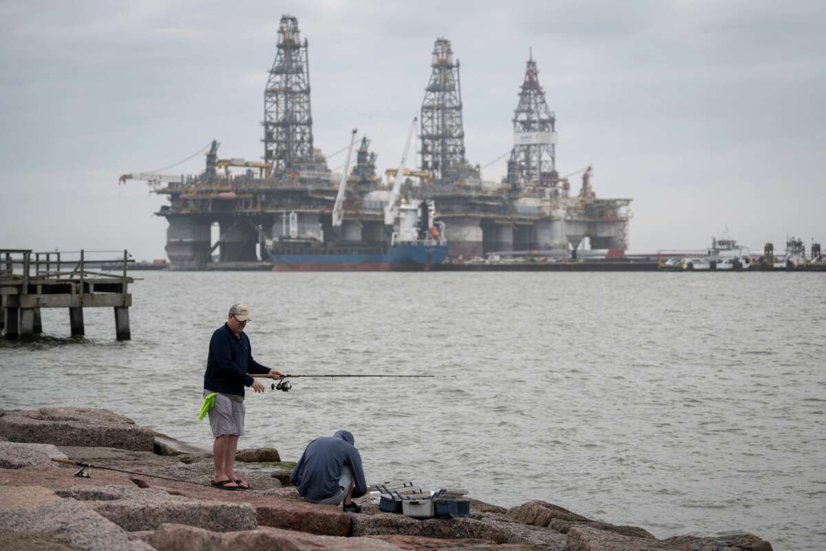 People fish in front of defunct oil drilling rigs in the Corpus Christi Ship Channel at Aransas Pass in Port Aransas, Texas, on March 11, 2019.