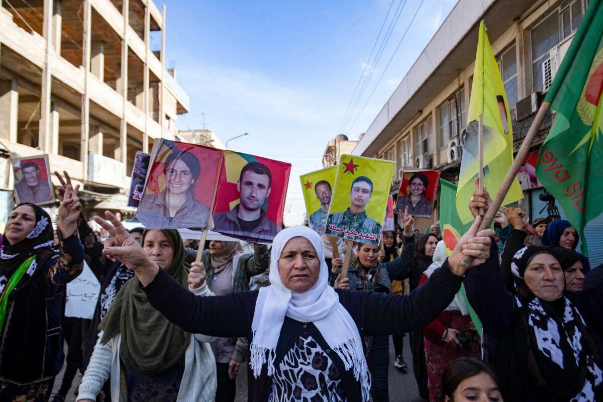 Syrian-Kurdish demonstrators wave flags and raise pictures of people killed during conflict