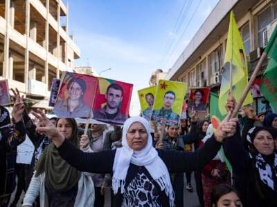 Syrian-Kurdish demonstrators wave flags and raise pictures of people killed during conflict