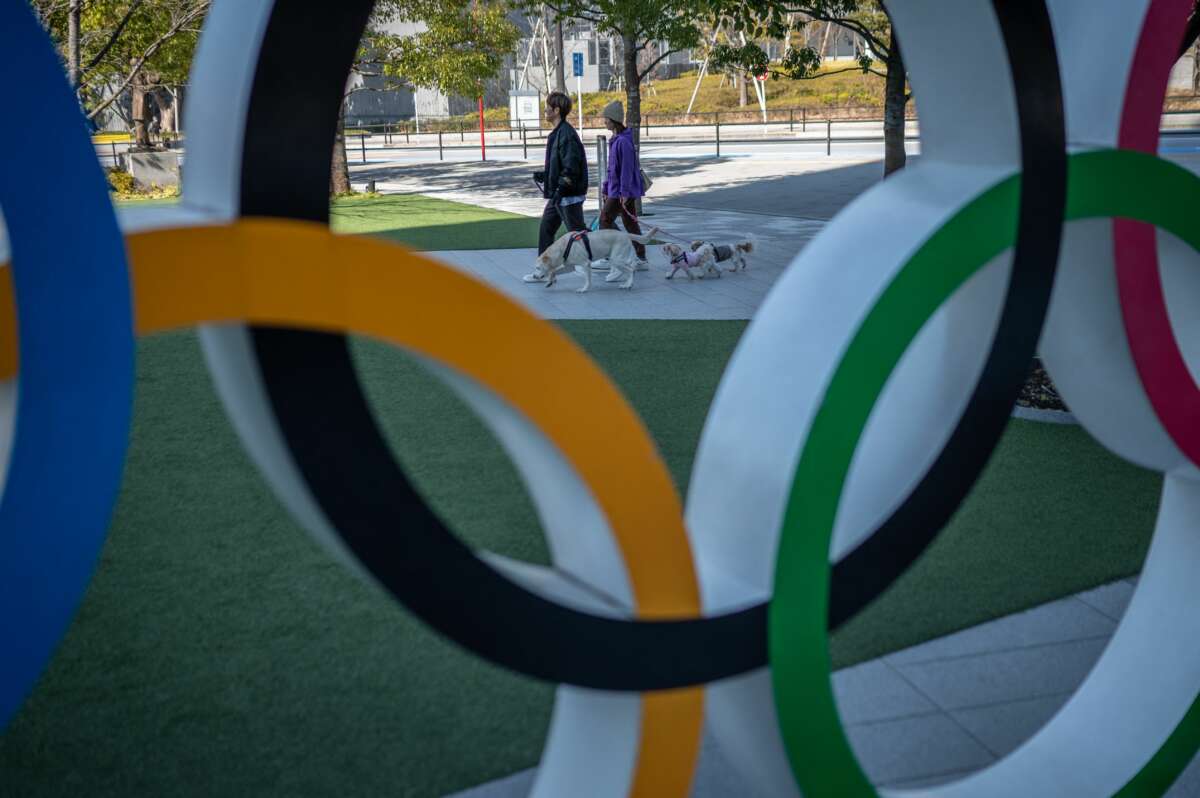 People walk their dogs past the Olympic rings near the National Stadium in Tokyo, Japan, on February 17, 2023.