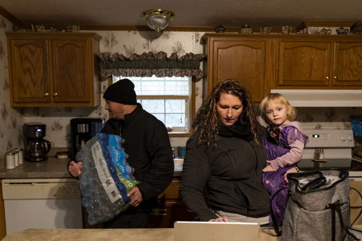 A man carries a case of water into his home near East Palestine, Ohio