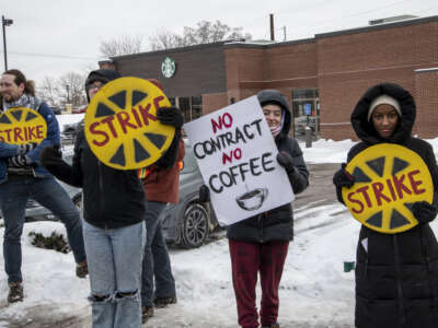 Starbucks workers strike outside in the snow holding signs that say "No contract no coffee"
