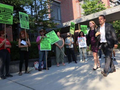 People walk past activists as they participate in an event dubbed the Un-Birthday Party and picket line for Starbucks CEO Howard Schultz on July 19, 2022, in New York City.