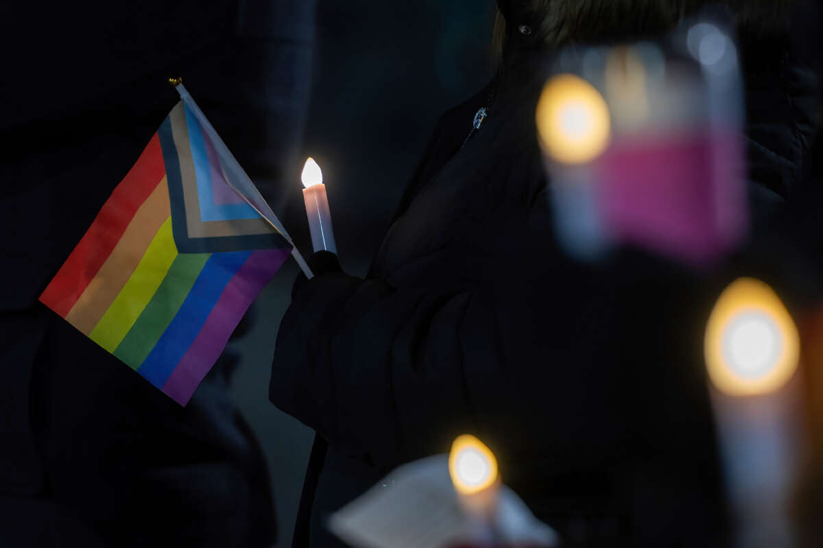A person holds a Pride flag as others hold candles during a vigil on evening of Transgender Day of Remembrance, on November 11, 2022, in Wiles-Barre, Pennsylvania.