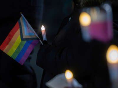 A person holds a Pride flag as others hold candles during a vigil on evening of Transgender Day of Remembrance, on November 11, 2022, in Wiles-Barre, Pennsylvania.