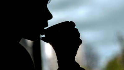Person drinks from cup in silhouette