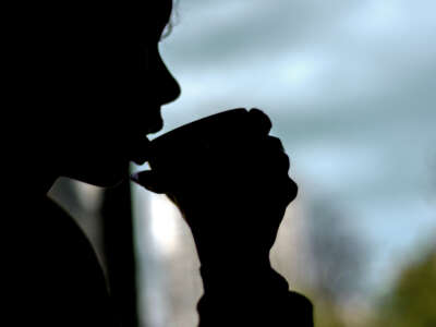 Person drinks from cup in silhouette