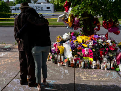 People pay their respects at a makeshift memorial across the street from Tops Friendly Market at Jefferson Avenue and Riley Street on May 18, 2022, in Buffalo, New York.