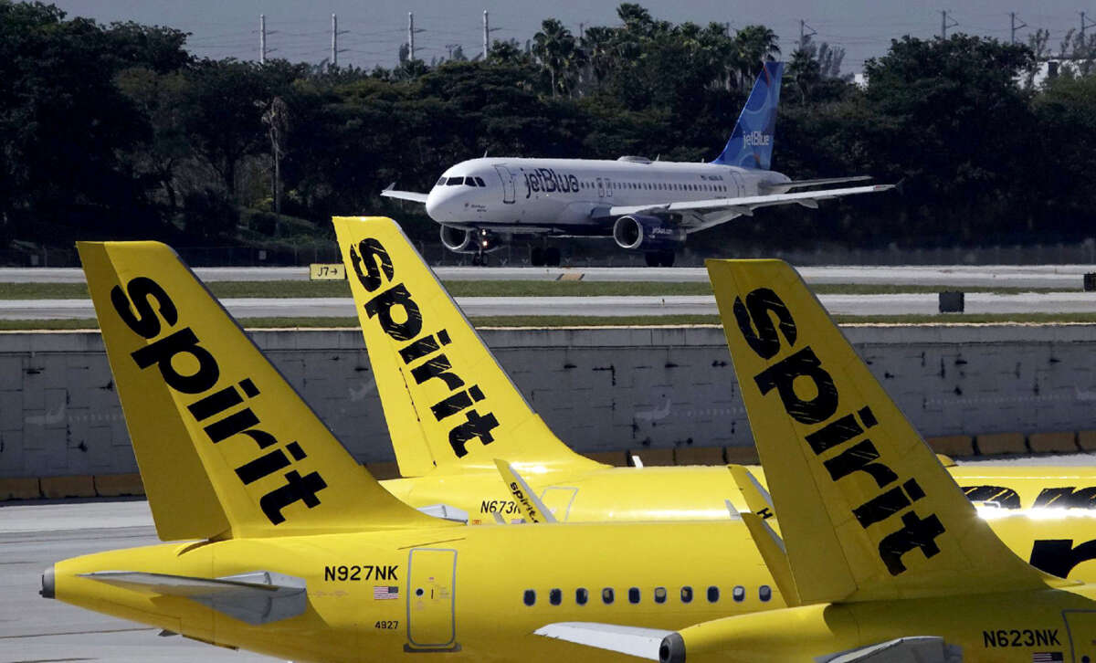 A JetBlue airliner takes off past Spirit Airlines planes at Fort Lauderdale-Hollywood International Airport.