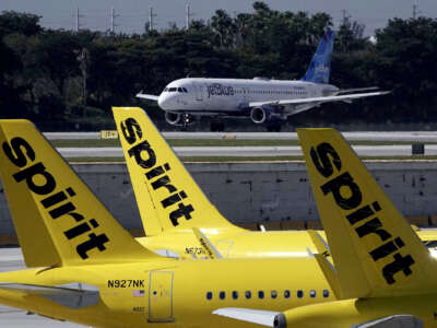 A JetBlue airliner takes off past Spirit Airlines planes at Fort Lauderdale-Hollywood International Airport.