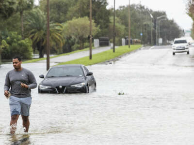 A man leaves his car behind to struggle through shin-deep floodwater