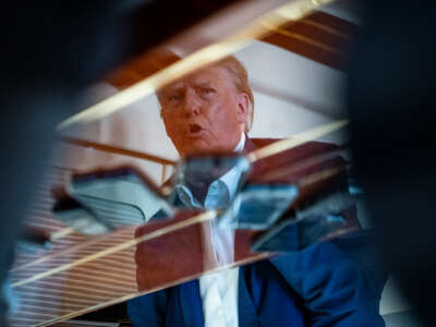 Former President Donald Trump speaks with reporters and staff in West Palm Beach, Florida, as he prepares to leave for Iowa on his airplane Trump Force One, on Monday, March 13, 2023.