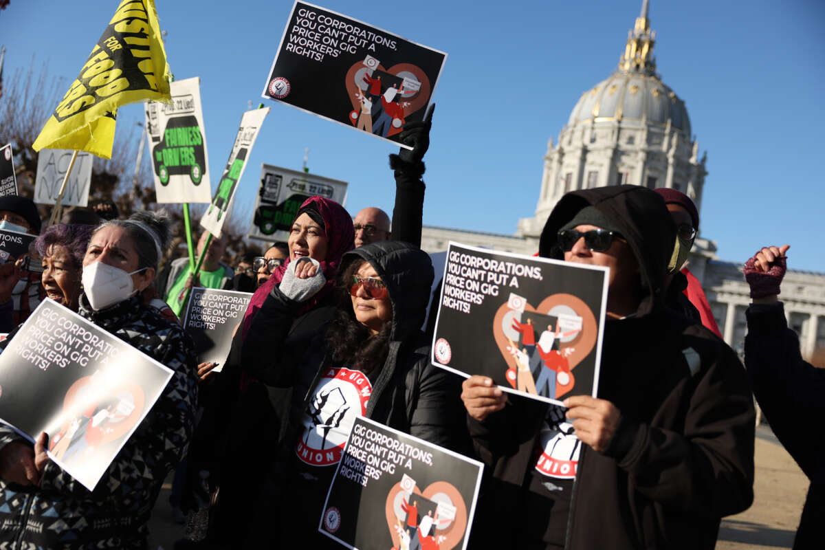 Gig workers with the California Gig Workers Union hold signs during a rally against Proposition 22 outside of the California First Appellate District Court of Appeal on December 13, 2022, in San Francisco, California.