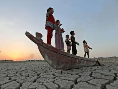Children stand on a boat lying on the dried-up bed of Iraq's receding southern marshes of Chibayish in Dhi Qar province, on July 24, 2022.