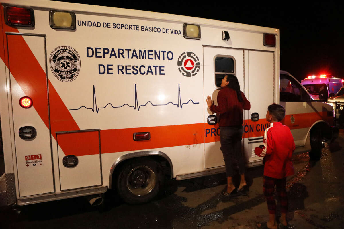 A Venezuelan migrant cries next to an ambulance in which her husband, who was injured in a fire, is being transported following a fire at the immigration station in Ciudad Juarez, Chihuahua state on March 28, 2023, where at least 39 people were killed and dozens injured after a fire at the immigration station.