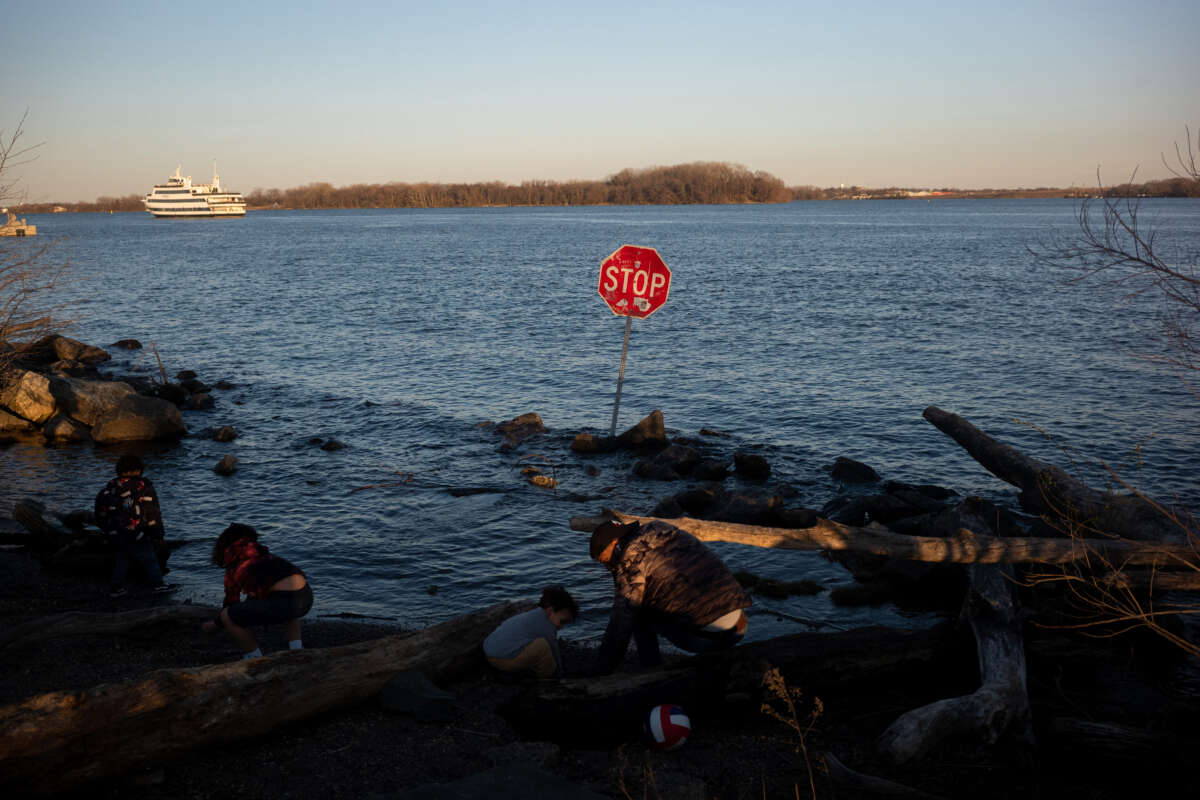 Children play along the Delaware River where a stop sign has been placed in the water at Penn Treaty Park in Philadelphia, Pennsylvania, on March 26, 2023.
