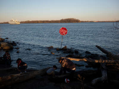 Children play along the Delaware River where a stop sign has been placed in the water at Penn Treaty Park in Philadelphia, Pennsylvania, on March 26, 2023.