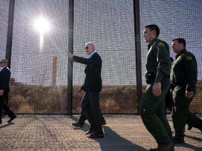 Joe Biden walks alongside border patrol agents and beside the us/mexio border fence