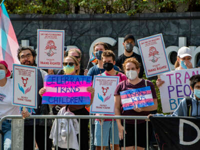 People holding supportive signs bearing the trans flag colors protest in support of the trans and gender-nonconforming communities