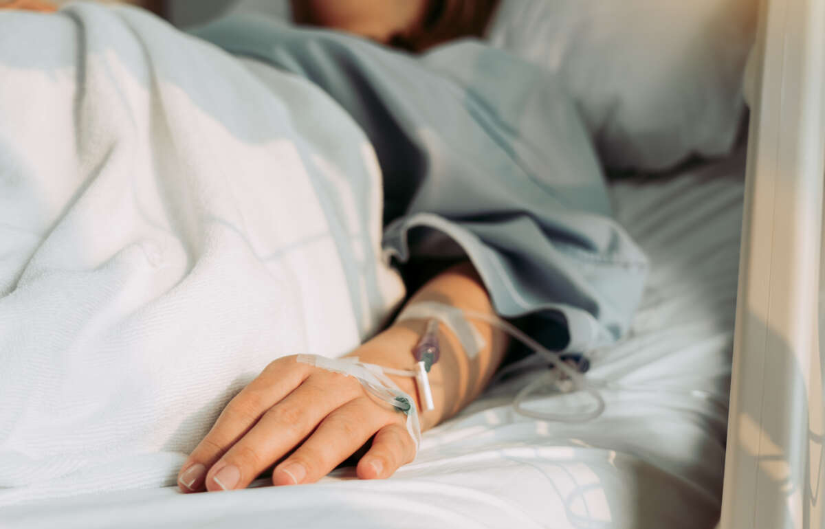 Woman lies in hospital bed connected to IV