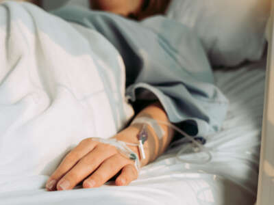 Woman lies in hospital bed connected to IV